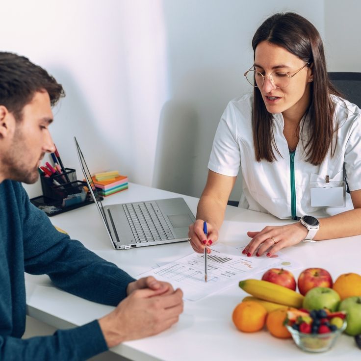 Nutricionista da Arena Academia orientando aluno com plano alimentar sobre a mesa